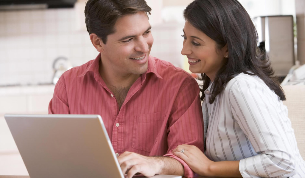 Couple in the kitchen viewing their laptop updates, London City Mortgages