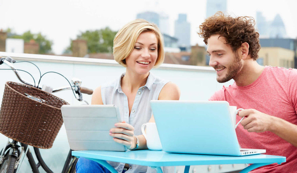 Couple on aroof terrace viewing notices on their tablet and laptop, London City Mortgages