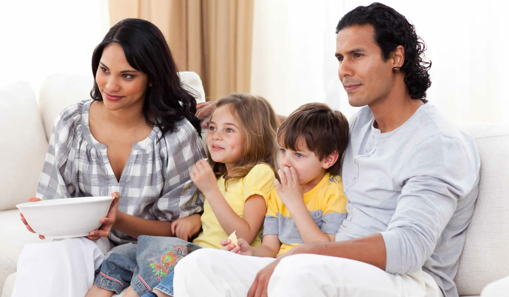 Family of four watching television in their livingroom, London City Mortgages