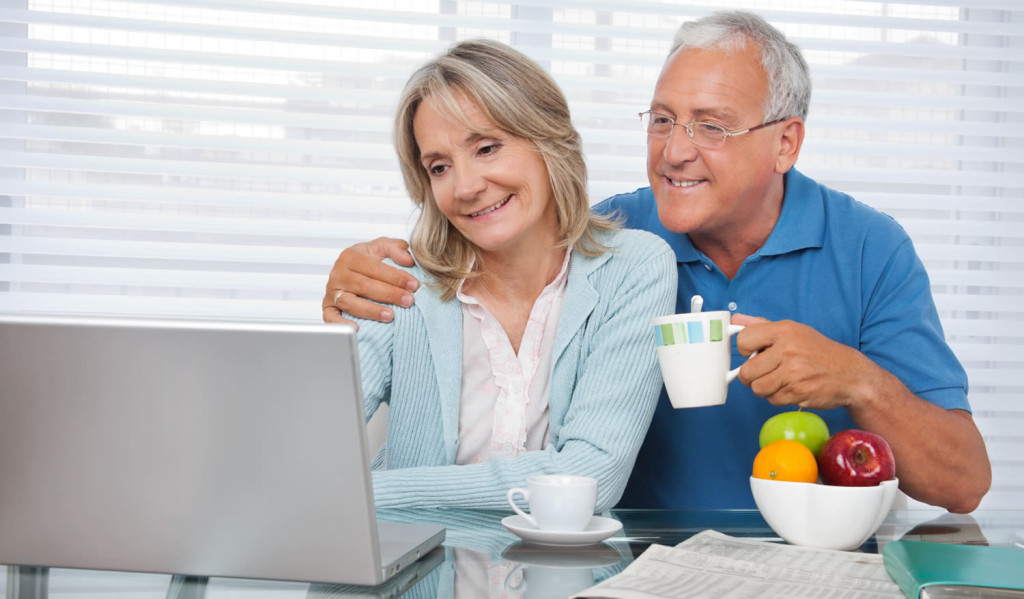 Happy older couple at home drinking tea accessing their laptop news, London City Mortgages