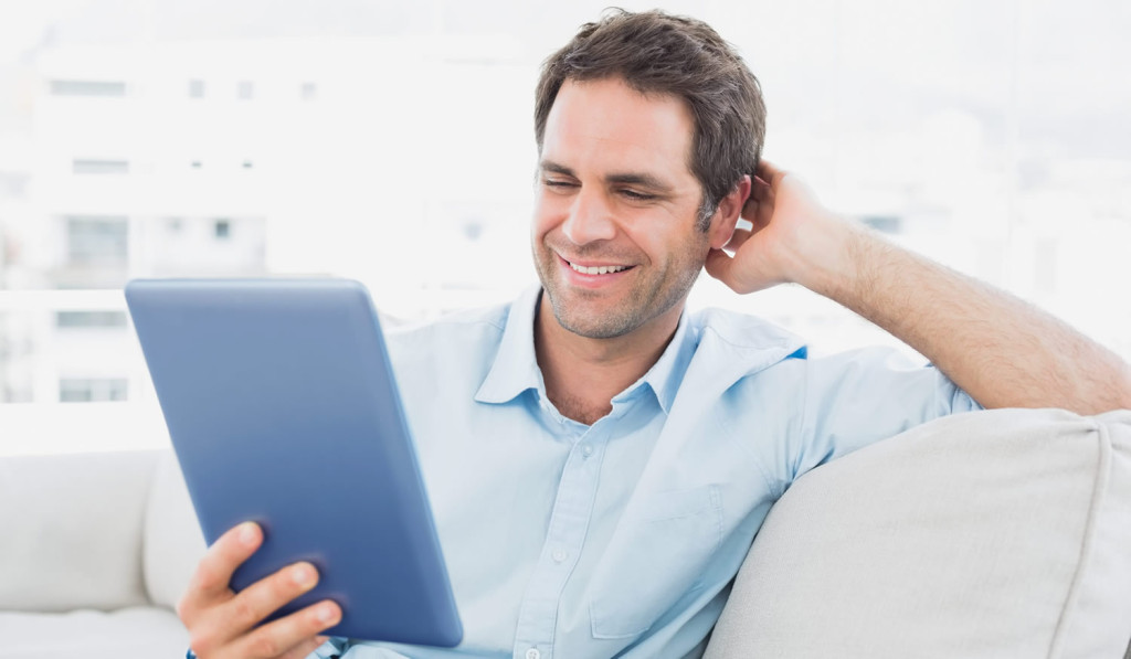 Man at home on his sofa accessing his tablet news, London City Mortgages