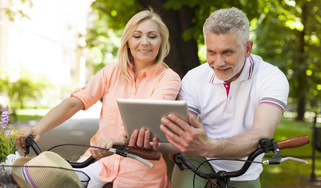 Middle age couple in the park accessing their tablet notices, London City Mortgages