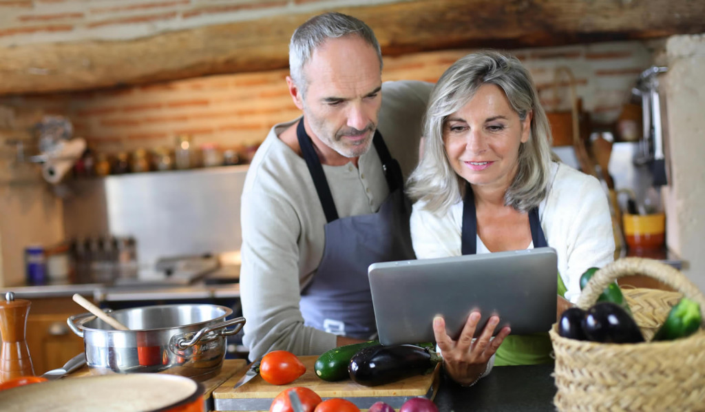 Older couple in home kitchen reviewing their tablet notices, London City Mortgage