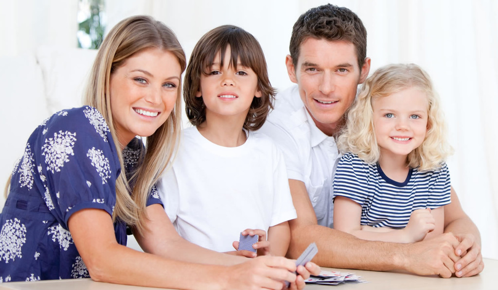 Smiling family playing cards at home, London City Mortgages