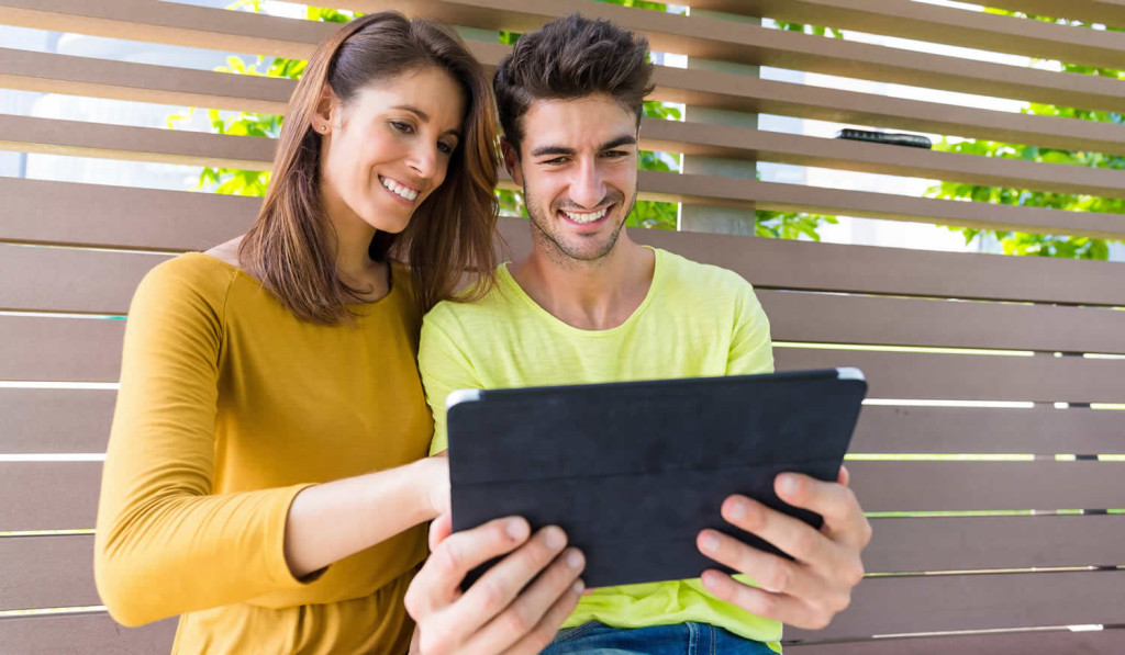 Young couple outdoors viewing updates on their tablet, London City Mortgages