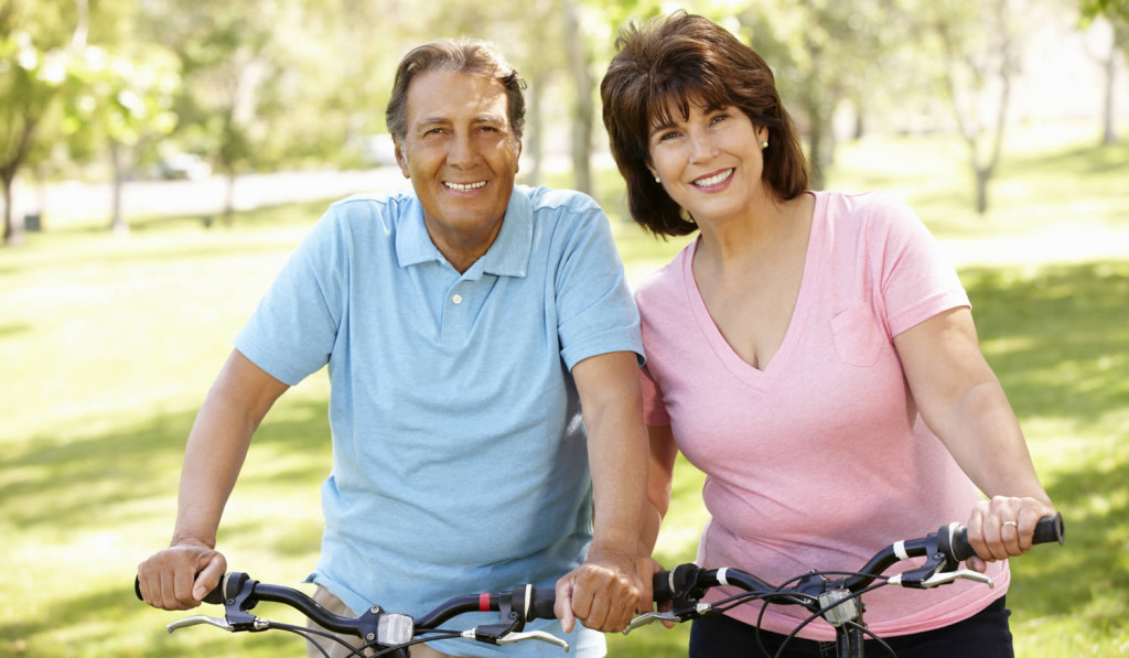 Active mature couple cycling in park London City Mortgages