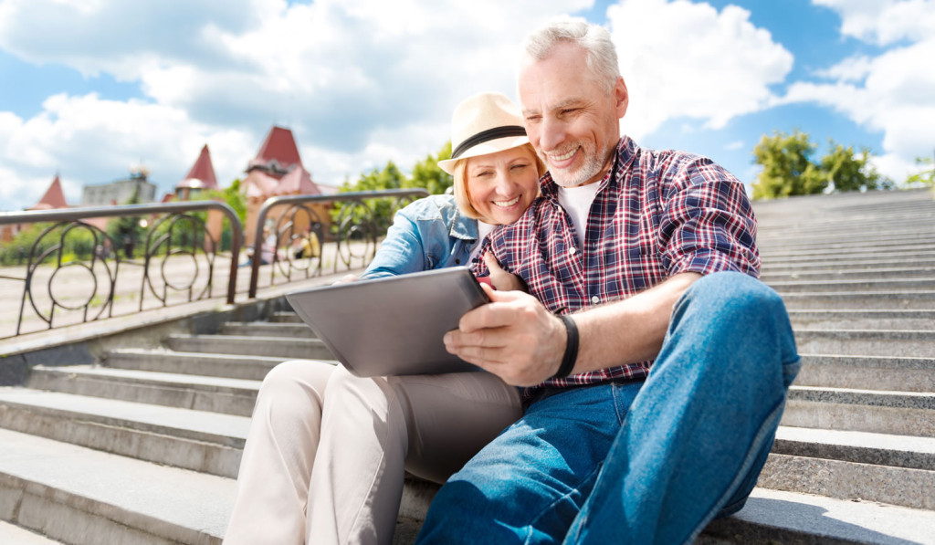 Bright outdoors mature couple on tablet London City Mortgages