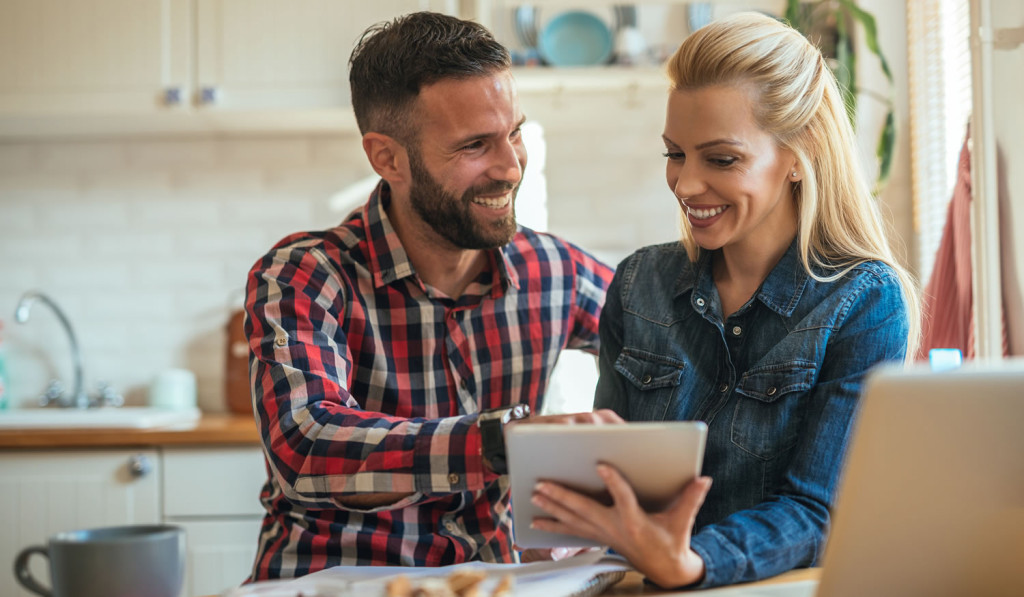 Kitchen smiling couple with tablet and laptop London City Mortgages