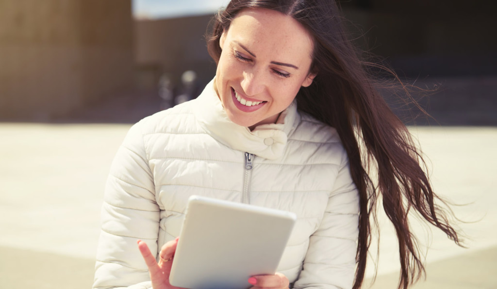 Sunny outdoors with young woman on tablet London City Mortgages