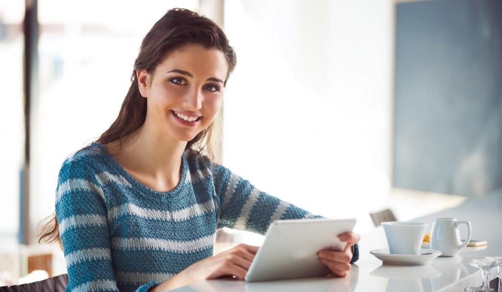 Woman in coffee shop reading tablet news London City Mortgages